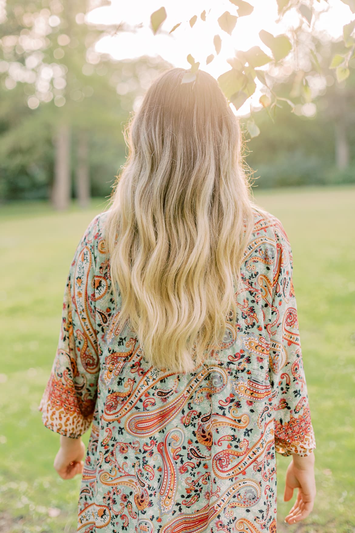 Frau mit blonden Haaren und Kimono in der Abendsonne im Park