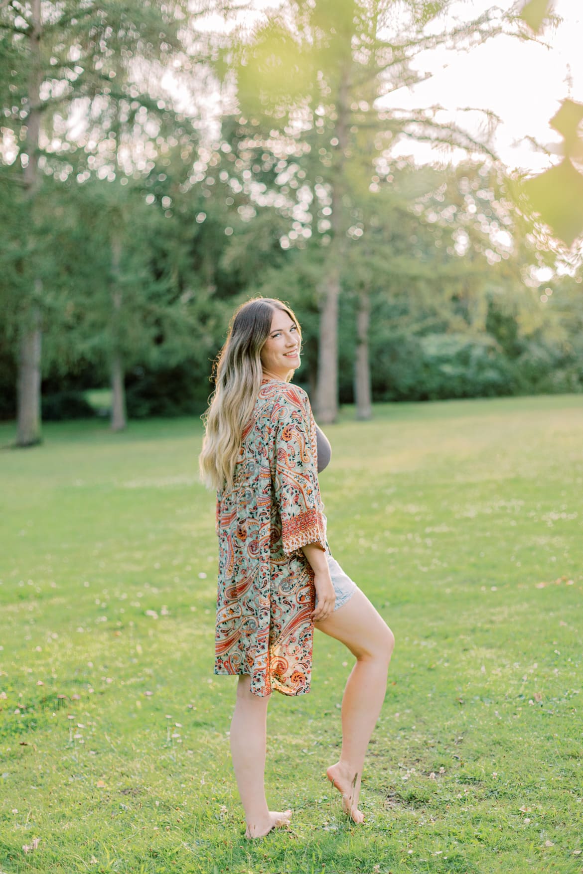 Frau mit blonden Haaren und Kimono in der Abendsonne im Park